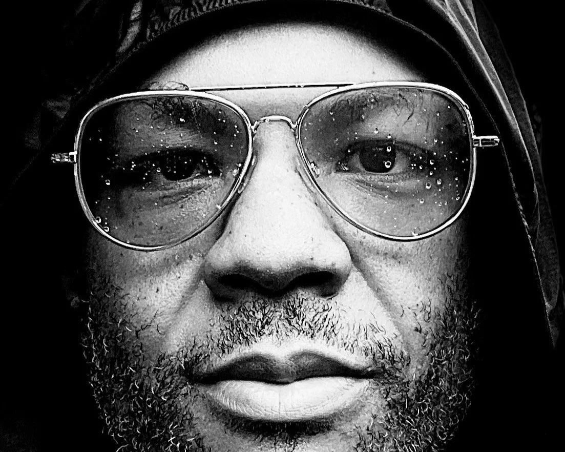 Close-up portrait of Chris Hardy wearing sunglasses in the rain